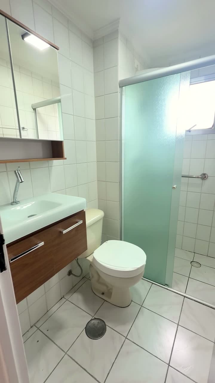 Banheiro com gabinete, vaso e box de vidro