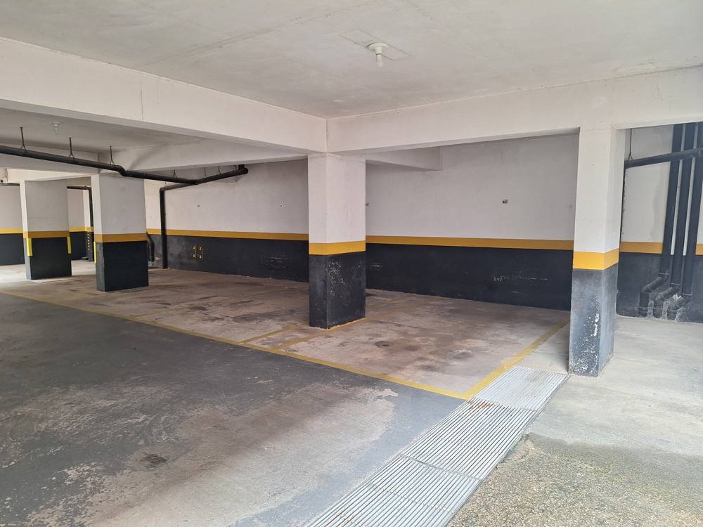 Garagem coberta do condomínio com vagas demarcadas