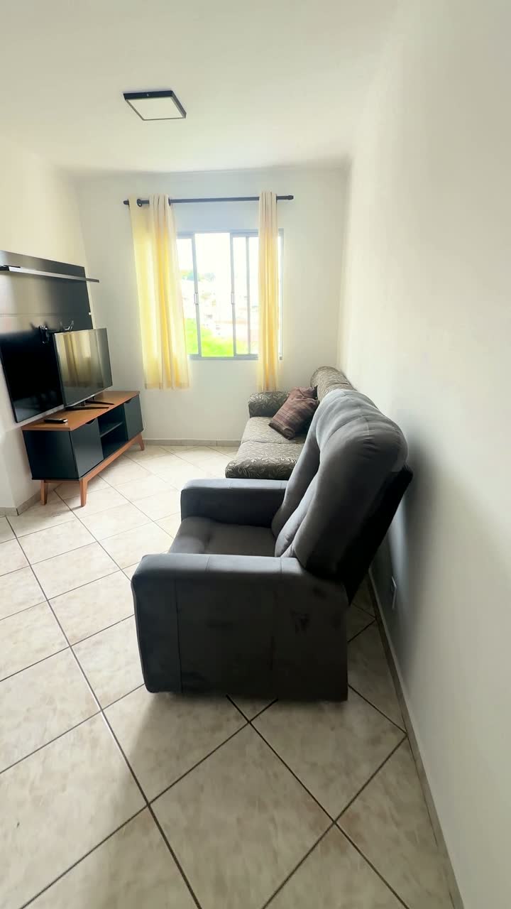Sala com sofá, rack e janela com cortina
