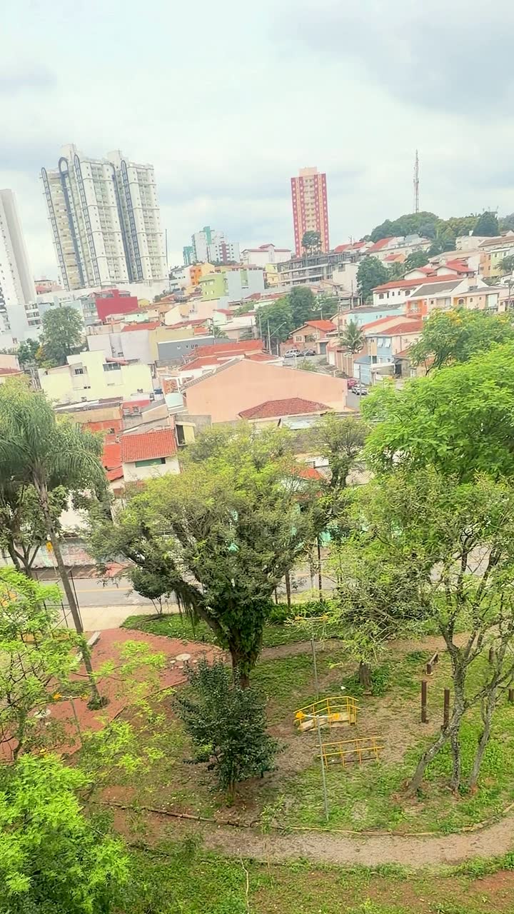 Vista da janela do segundo quarto: praça com árvores e o bairro